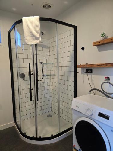 a shower with a glass door next to a washing machine at Simply Stunning Stars A in Lake Tekapo