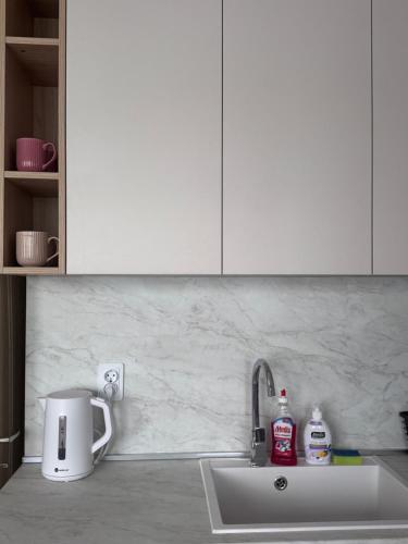 a kitchen counter with a sink and white cabinets at Апартамент Кари in Yambol