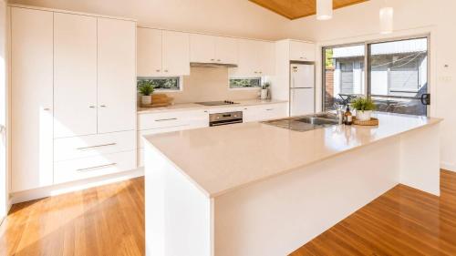 a kitchen with white cabinets and a wooden floor at Anchor at Bawley in Bawley Point