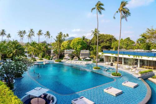 an aerial view of a resort pool with lounge chairs and palm trees at Meliá Koh Samui in Choeng Mon Beach