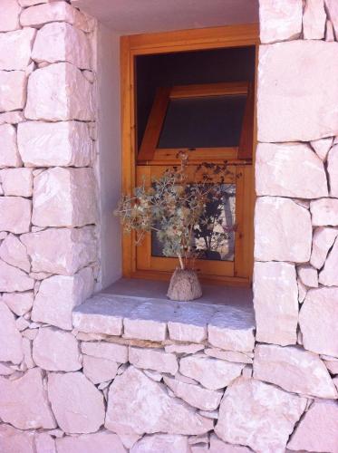 a window in a stone wall with a vase with flowers at Casa Bedda in Noto Marina