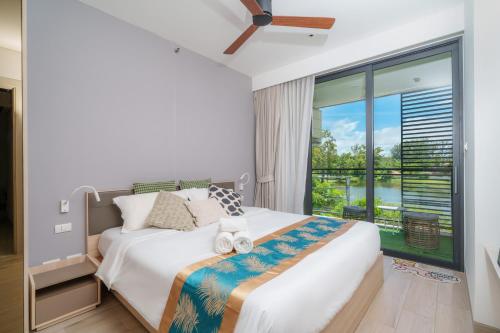 a bedroom with a bed and a large window at Cassia Apartment 1 in Bang Tao Beach