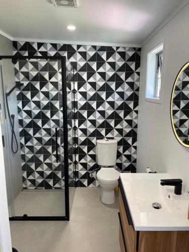 a bathroom with a black and white tiled wall at Black Box Bach in Coopers Beach