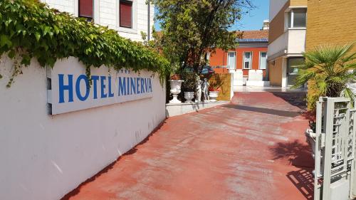 un cartel del ministerio del hotel al lado de un edificio en Hotel Minerva, en Pordenone