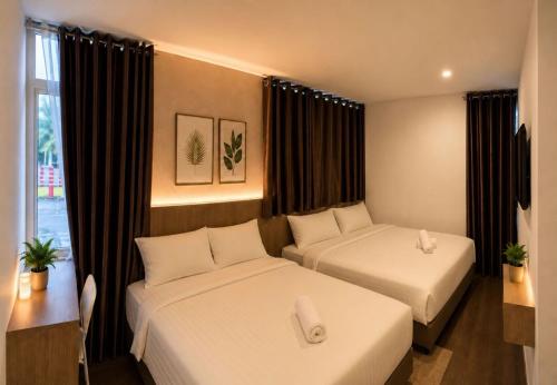 a hotel room with two beds and a window at Point Stay GH in Kuching