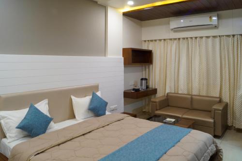 a bedroom with a bed and a couch at Hotel Midtown in Vadodara