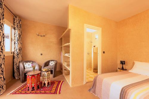 a bedroom with a bed and a chair and a table at Aftas Trip in Mirleft