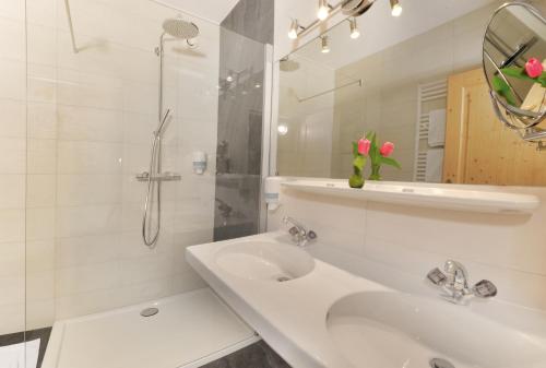 a white bathroom with a sink and a shower at Apparthotel Thalerhof in Mayrhofen