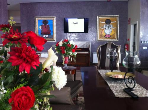 a living room with red flowers and a piano at Hotel Sevilla in Ronda