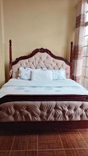 a large bed with a large headboard in a bedroom at Oundo LVHAR in Busia