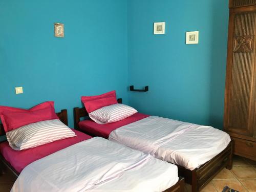 two beds in a room with a blue wall at The Olive Tree House in Kompítsion