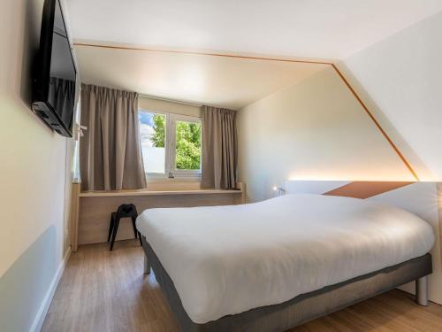 a hotel room with a large bed and a tv at Ibis budget Chambéry Centre Ville- Hôtel Rénové in Chambéry