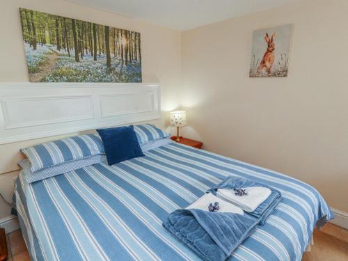 a bedroom with a bed with blue and white stripes at Piggery Cottage in Wigton