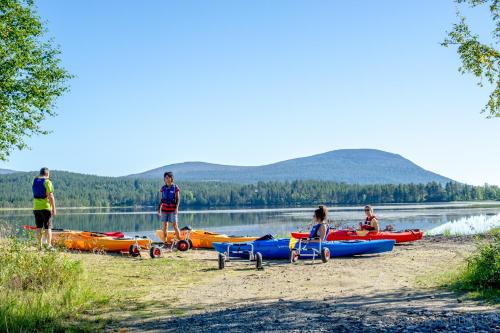 a group of people on a beach with kayaks on a lake at Ylläksen Yöpuu in Äkäslompolo