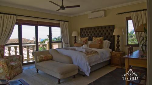 a bedroom with a bed and a chair and windows at The Villa Umhlanga in Durban