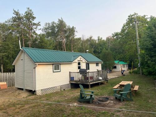 a white cabin with a green roof and a picnic table at Private Beach Access -Cottage 15 in Sauble Beach