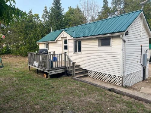 a small white house with a porch and a staircase at Private Beach Access -Cottage 15 in Sauble Beach