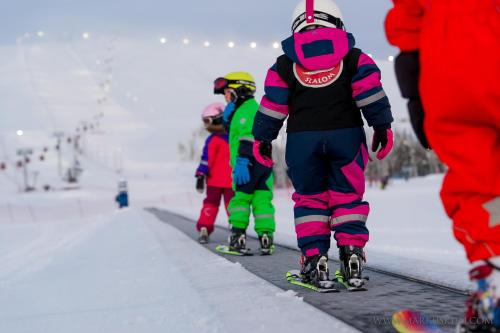 a group of people skiing down a snow covered slope at Ylläksen Yöpuu in Äkäslompolo