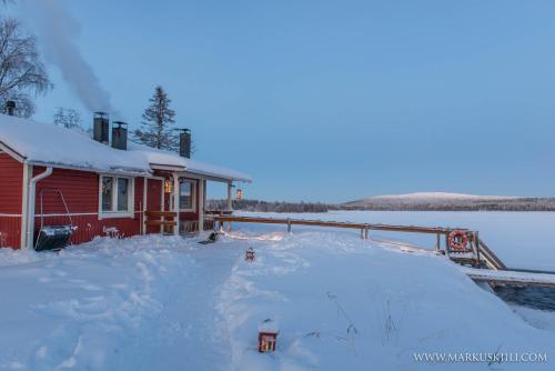 a house covered in snow next to a body of water at Ylläksen Yöpuu in Äkäslompolo