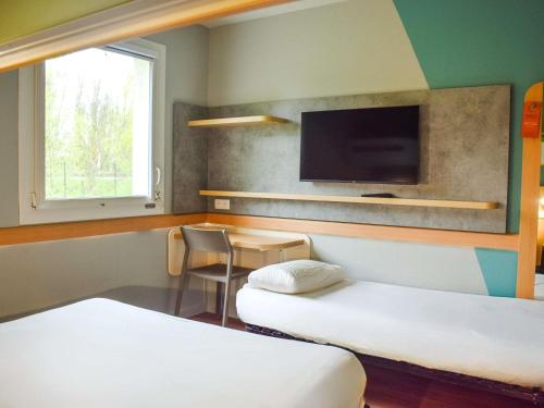 a room with two beds and a flat screen tv at ibis budget Rodez in Rodez