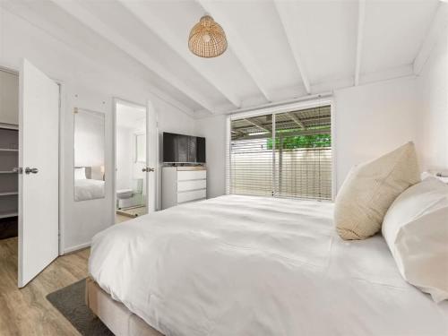 a white bedroom with a large bed and a window at Pepper Cottage - Easy Beachside Living Close to Town in Dunsborough