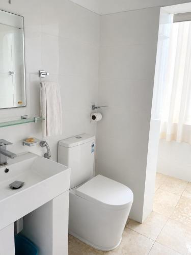 a white bathroom with a toilet and a sink at Ayubowan Home Stay - Kotikawatta in Angoda