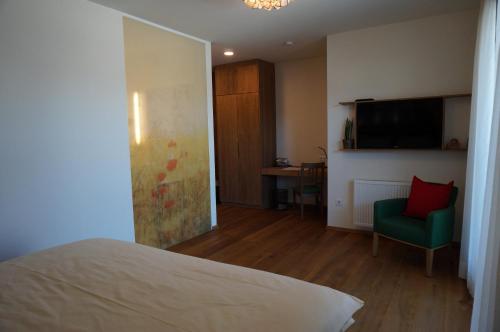 a bedroom with a bed and a chair and a television at Weingut und Gästezimmer Perner in Ehrenhausen