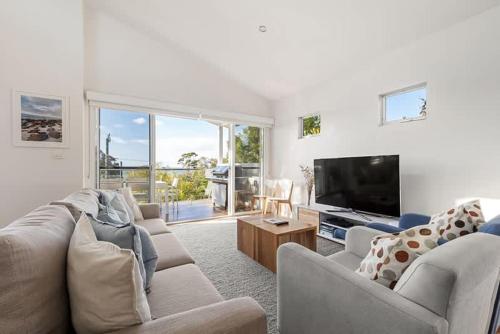 a living room with couches and a flat screen tv at Casa Bianca - Oceanview Beachside Escape in Dunsborough