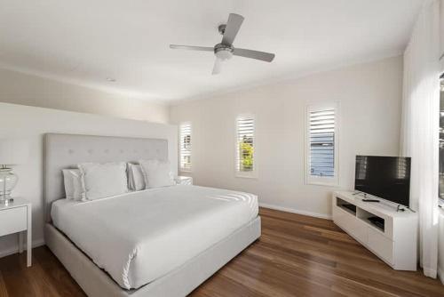 a white bedroom with a bed and a flat screen tv at Casa Bianca - Oceanview Beachside Escape in Dunsborough