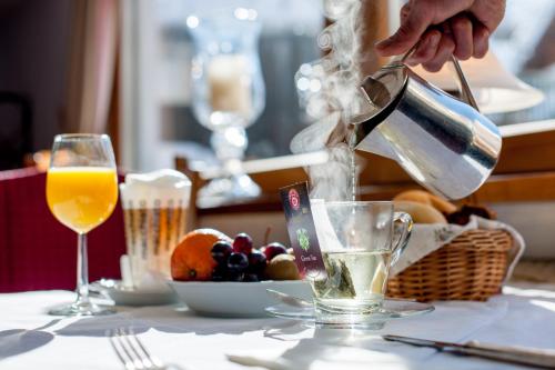 a person pouring an orange juice into a glass at Ski Hotel Mondschein 1739 in Stuben am Arlberg