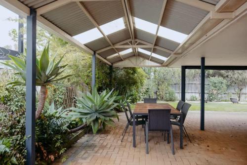 an outdoor patio with a wooden table and chairs at Luxury at the Cove - Seaside Comfort & Entertainment in Quindalup