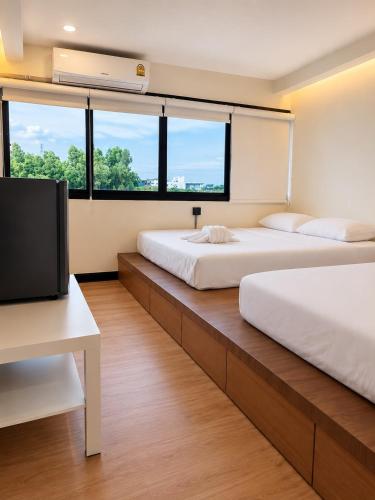 a bedroom with two beds and a flat screen tv at Sukhum Ratchada Sutthisan in Bangkok