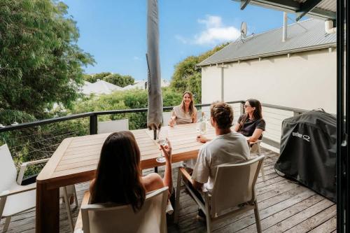 a group of people sitting around a table on a deck at Blue Haven Townhouse - Beachside Retreat with Pool Access in Gnarabup