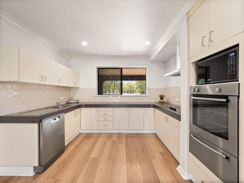 a kitchen with white cabinets and stainless steel appliances at Bluewater Retreat - Pet-Friendly Coastal Oasis in Broadwater