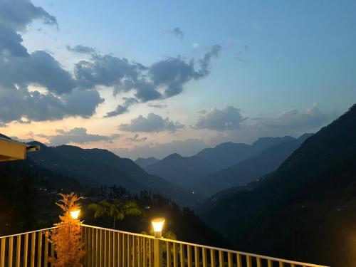 a view of a valley from a balcony with lights at Echor Mountain Crest Jibhi in Jibhi