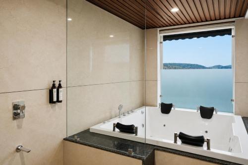 a bathroom with a tub and a large window at Aamba Bagh Resort Kumbhalgarh in Kumbhalgarh