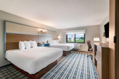 a hotel room with two beds and a television at AmericInn by Wyndham Hutchinson in Hutchinson