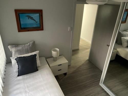 a bedroom with a white bed and a mirror at Seaside Breezes with Wi-fi in Slade Point