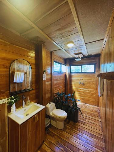 a wooden bathroom with a toilet and a sink at Oasis Manzanillo Del Mar in Manzanillo del Mar
