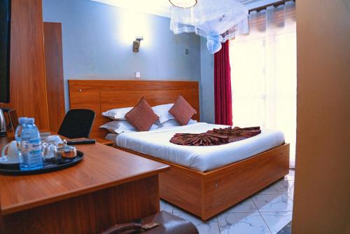 a bedroom with a bed and a desk with a desk at Golden Quest Hotel in Entebbe