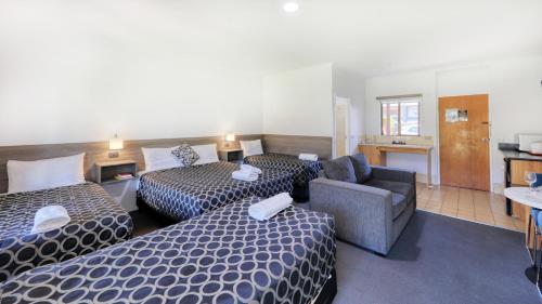 a hotel room with two beds and a couch at The Cottage Motor Inn Albury CBD in Albury