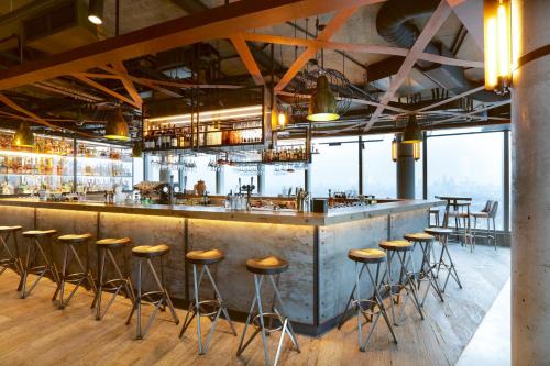 a bar with stools in a room with windows at Novotel London Canary Wharf in London