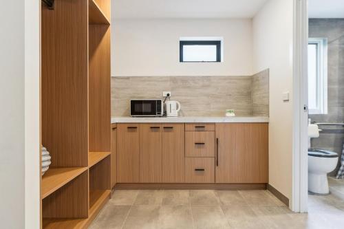 a kitchen with wooden cabinets and a microwave at Frankston Bay Motel in Frankston