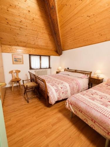 a bedroom with two beds and a wooden ceiling at Dolomiti House in Pinzolo