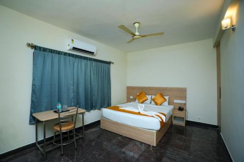 a bedroom with a bed and a table and a desk at PP Residency in Covelong