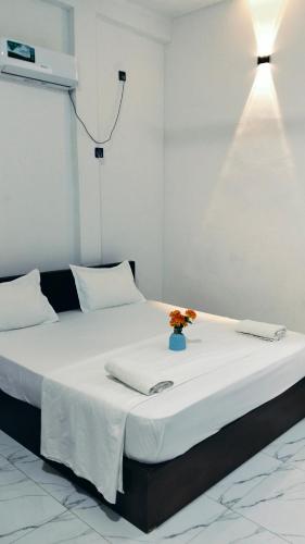 a large white bed with a vase of flowers on it at Calm Night Surf Stay in Arugam Bay