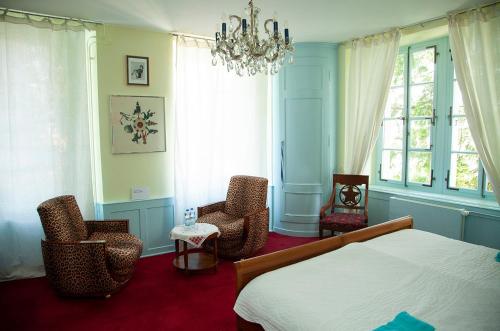a bedroom with a bed and chairs and a chandelier at BnB villaSteiner in Birrwil