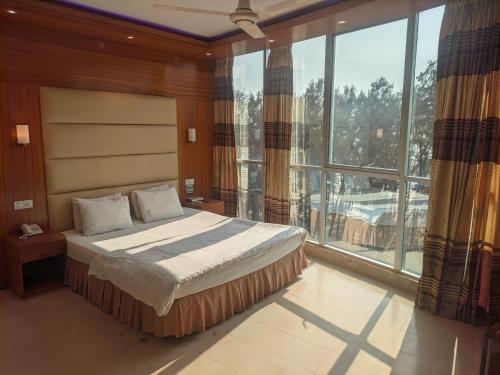a bedroom with a bed and a large window at Praasad Paradise in Cox's Bazar