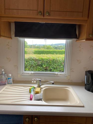 a kitchen sink with a window with a view of a field at Craigmore Caravan in Coleraine