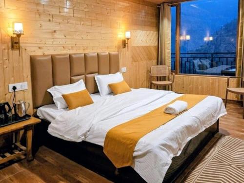a bedroom with a large bed with a large window at The Kailash Glint in Kalpa